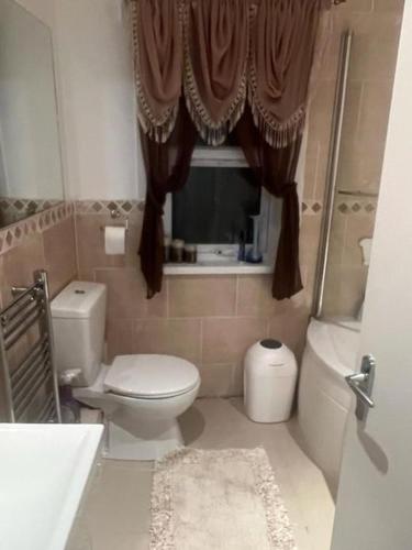 a bathroom with a toilet and a window at HAPPY HOURS HOME STAY in London
