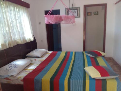 a bedroom with a bed with a colorful striped blanket at Grace Villa Bentota in Bentota