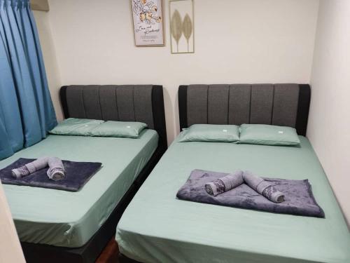 Dos camas en una habitación con zapatos. en Tanjung tuan regency private PD en Port Dickson