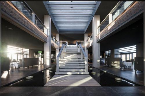 a lobby with stairs and tables and chairs in a building at ADLER Spa Resort SICILIA in Siculiana