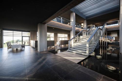 a lobby with a staircase and a table and chairs at ADLER Spa Resort SICILIA in Siculiana