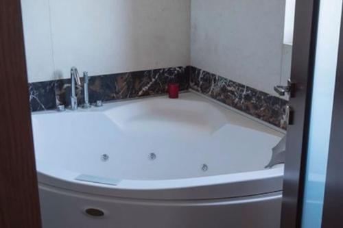 W łazience znajduje się biała umywalka i wanna. w obiekcie Deluxe οροφοδιαμέρισμα με υδρομασάζ κ' ταρατσόκηπο w mieście Patras