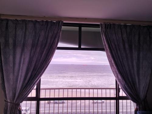 una ventana con cortinas y vistas al océano en 504 Witsand en Bloubergstrand