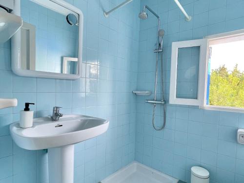 a blue bathroom with a sink and a shower at Casa frente al lago in La Savina