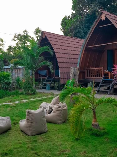 a group of pillows on the grass in front of a house at Leaf Coco Bungalow in Gili Air