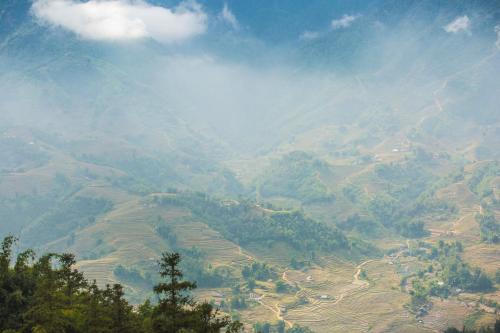 een uitzicht op een bergvallei met bomen en velden bij Sapa Jade Hill Resort & Spa in Sa Pa