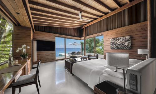 a bedroom with a bed and a desk and a tv at Park Hyatt Maldives Hadahaa in Gaafu Alifu Atoll
