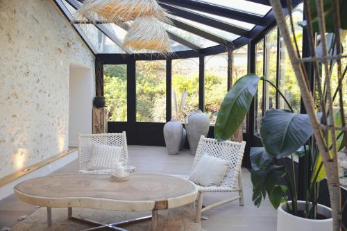 a patio with a table and chairs and windows at La maison Balinaise in Haravilliers