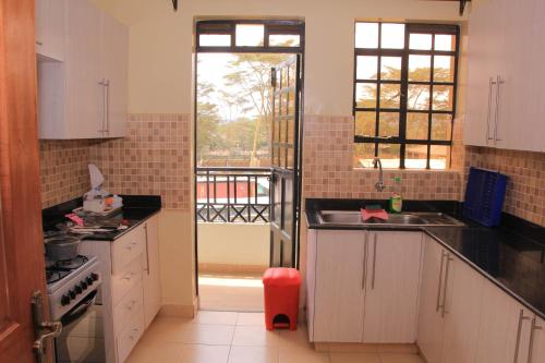 eine Küche mit einem Waschbecken und eine Tür zu einem Balkon in der Unterkunft BIDA FURNISHED APARTMENTS in Naivasha