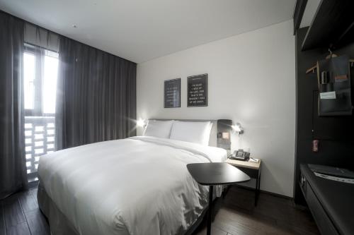 a bedroom with a large white bed and a table at GLAD Yeouido in Seoul