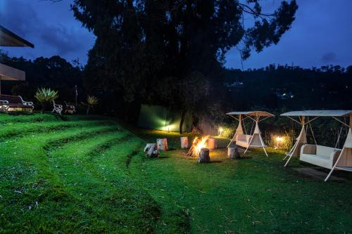 a campsite with a fire in the grass at night at Sterling Kodai Lake in Kodaikānāl