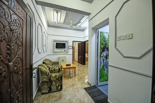 OYO 140 Al Musafir Hotel في بركاء: ممر مع غرفة معيشة مع كرسي وتلفزيون