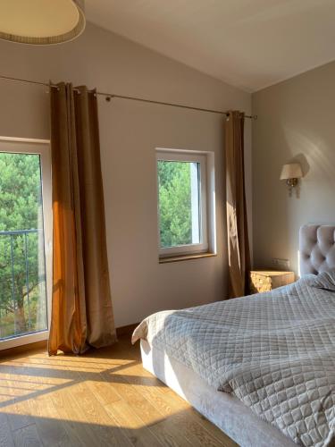 a bedroom with a bed and two windows at Bella luna vila Palanga with forest view in Palanga