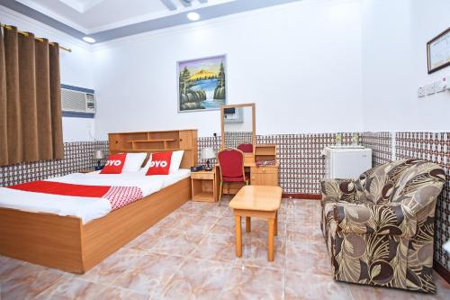 a bedroom with two beds and a desk and a chair at OYO 140 Al Musafir Hotel in Barka