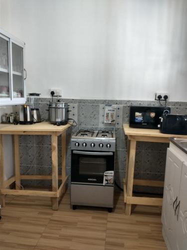 a kitchen with a stove and two wooden tables at Beautiful House Spintex Road Accra in Accra