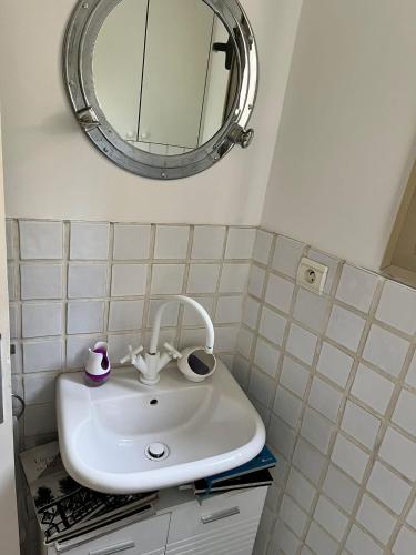 une salle de bain avec un lavabo blanc et un miroir dans l'établissement Une terrasse sur Monaco logement 2 chambre, à Beausoleil