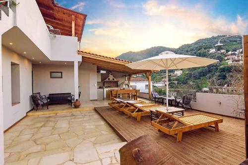 um pátio com mesas de madeira e um guarda-chuva em Villa Roxani em Mesklá