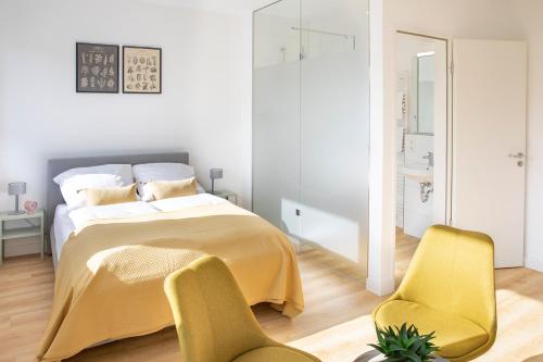 a bedroom with a bed and two yellow chairs at Louis & Louise Apartments & Rooms I Digital Check In in Bremen