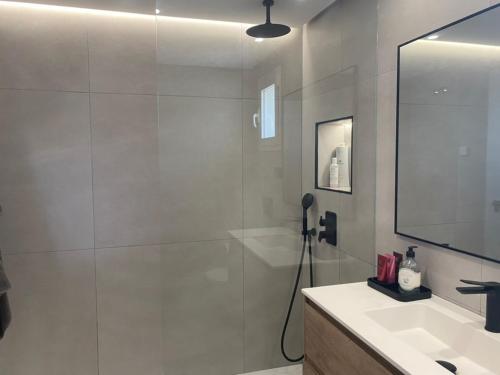 een badkamer met douche, wastafel en spiegel bij Precioso apartamento a pie de playa in Estepona