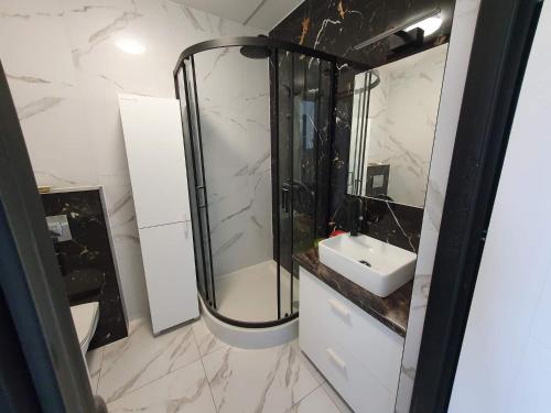 a white bathroom with a sink and a shower at Mieszkanie na wyłączność in Radomsko