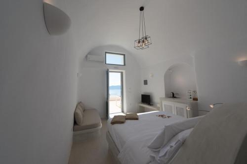 a white bedroom with a bed and a window at On the Cliff in Fira