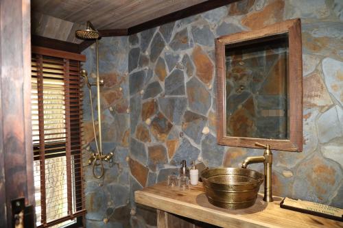 a bathroom with a sink and a stone wall at Amaya Retreat in Sóc Sơn