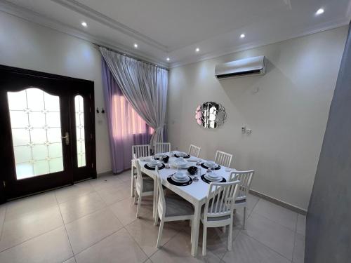 a dining room with a white table and chairs at Sasna in Doha