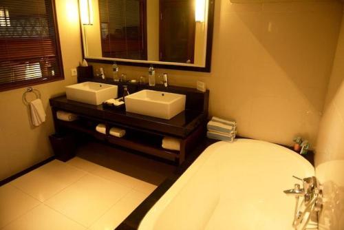 a bathroom with two sinks and a tub and a mirror at Cinta inn in Ubud