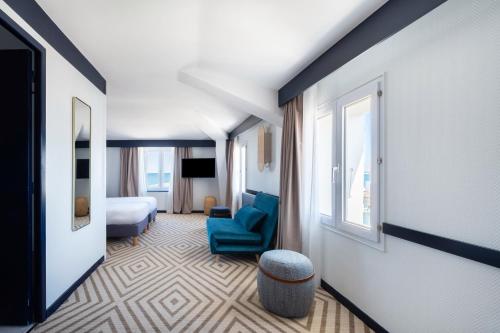 um quarto de hotel com uma cama e uma cadeira azul em Hôtel Le Français em La Flotte