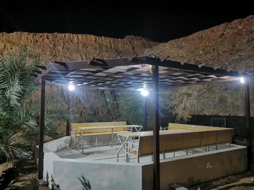 a patio with a table and benches at night at Al Hamra Guest House in Al Ḩamrāʼ