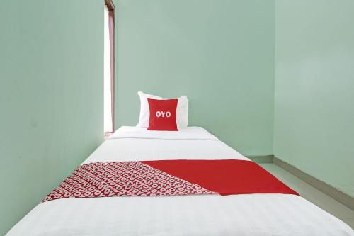 Una cama con una almohada roja encima. en OYO 91803 Gita Graha Guest House Syariah, en Yogyakarta