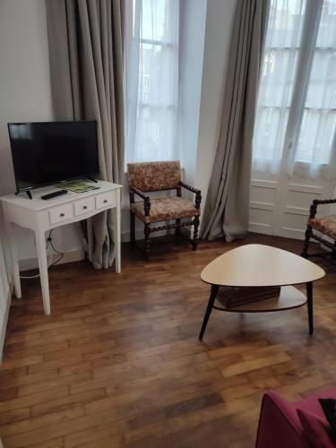 sala de estar con TV, mesa y sillas en Appartement 5 personnes proche du Mont Saint Michel, en Val Couesnon
