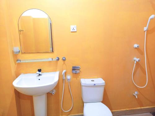 a bathroom with a sink and a toilet and a mirror at Sheen Holiday Resort in Tangalle