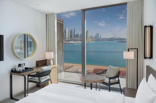 a bedroom with a bed and a desk and a view of the city at Radisson Beach Resort Palm Jumeirah in Dubai