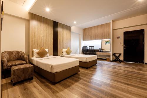 una habitación de hotel con 2 camas y una silla en Grand Marina Residence Hotel, en Ban Laem Chabang