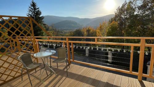 a table and chairs on a deck with a view at Dwupoziomowe Apartamenty Leszczyna in Ustroń