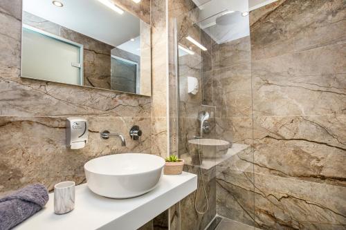 a bathroom with a sink and a mirror at New Azzurro Deluxe in Limenaria