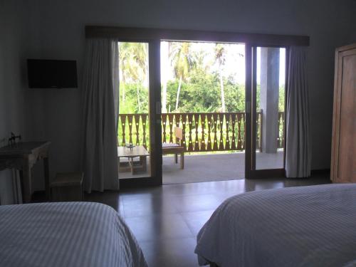 um quarto com uma cama e uma porta de vidro deslizante em Ju'Blu Hotel em Lovina