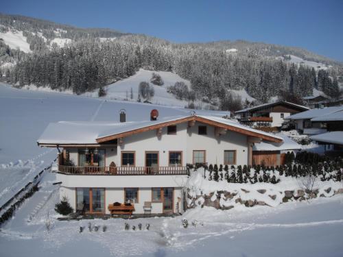 a house in the snow with people standing around it at Ferienwohnung am Lindenweg in Brixen im Thale