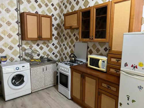 eine Küche mit einem Herd, einer Mikrowelle und einem Kühlschrank in der Unterkunft 2 х комнатная квартира in Schymkent