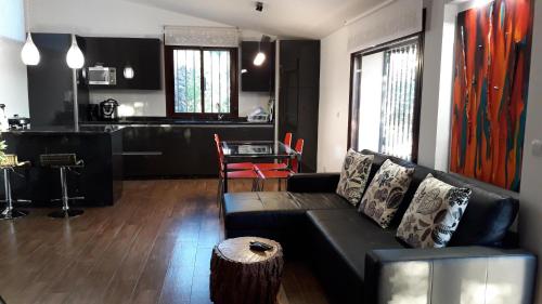 a living room with a black couch and a kitchen at Casa Rural La Recuera in Montánchez