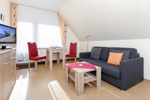 sala de estar con sofá azul y sillas rojas en Haus Lüttje Hörn en Bensersiel