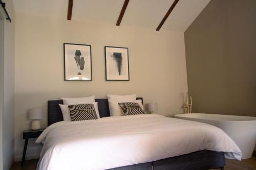 1 Schlafzimmer mit einem weißen Bett und einer Badewanne in der Unterkunft Logement In de Peel in Griendtsveen