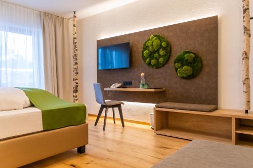 a bedroom with a bed and a desk and a tv at Hotel Lärchenhof in Katschberghöhe