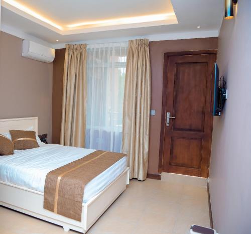 a bedroom with a bed and a television and a door at Hotel Amaranth in Dar es Salaam