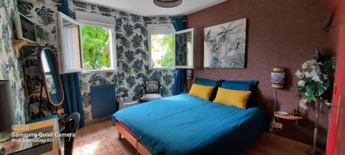 a bedroom with a bed with blue sheets and windows at Chambres d'hôtes Les Chênes in Acigné