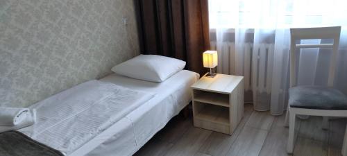 a small room with a bed and a table with a lamp at Hotel Polonia in Rzeszów
