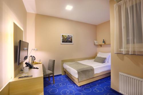 a bedroom with a bed and a desk and a television at Amarilis in Prague
