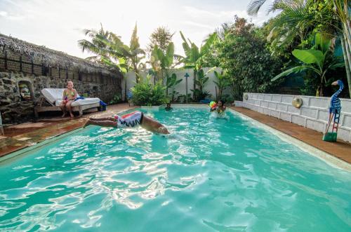 a person playing in a swimming pool with a dog at Les bungalows d'Ambonara in Hell-Ville