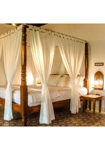 a bedroom with a canopy bed with white curtains at villa goa in Cola